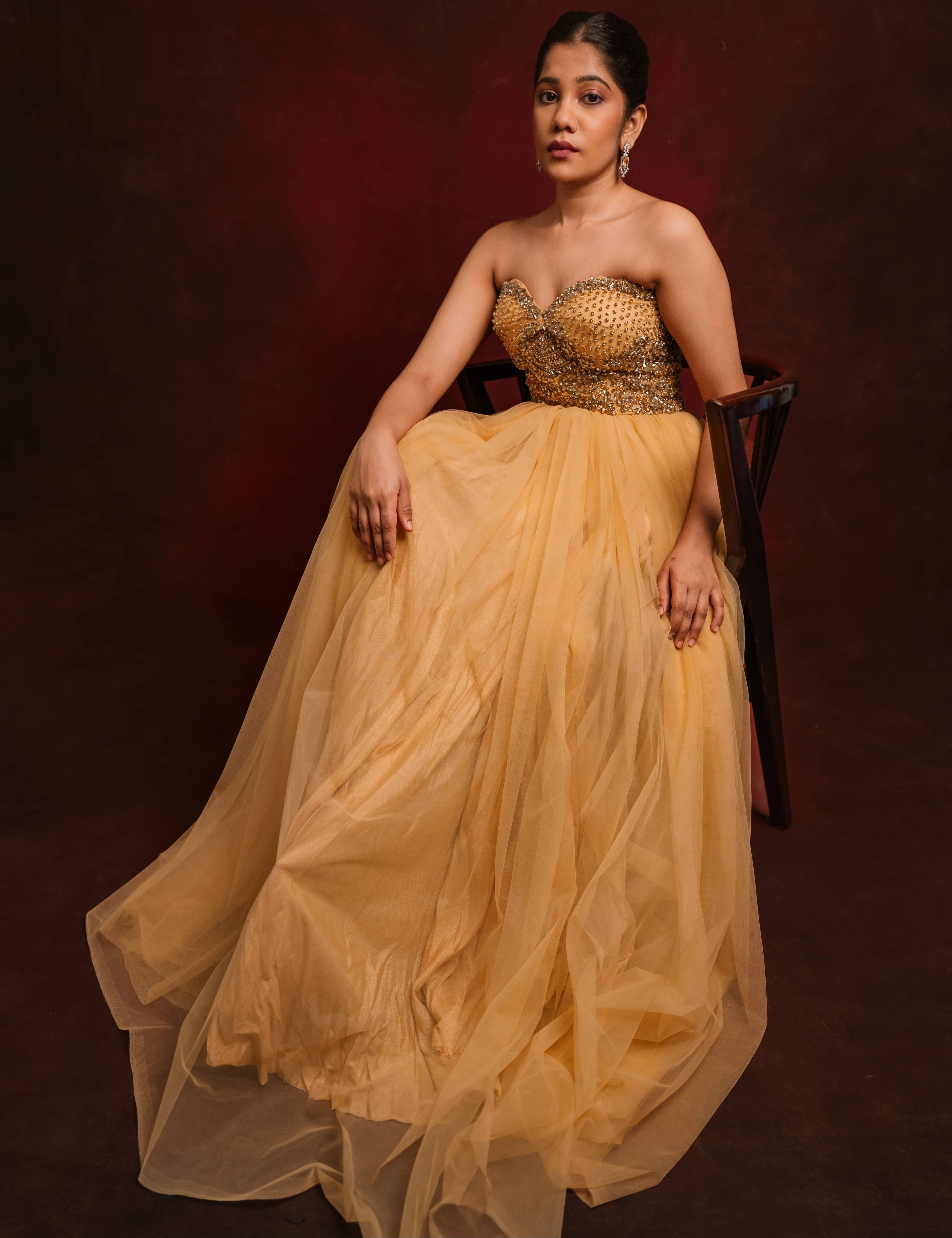 Posing straight in a gold corset dress intricately handcrafted with stones and sequins designed by team Archana Karthick.