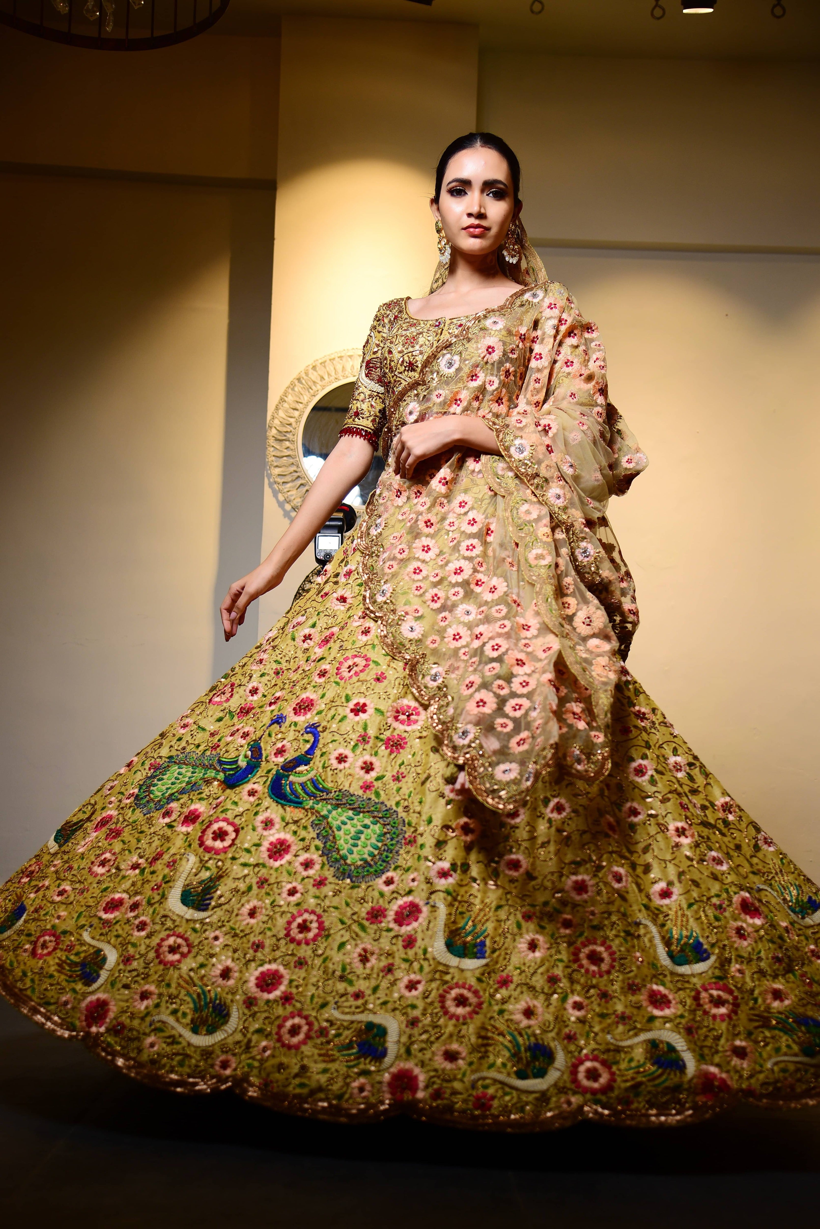 Model is posing mid-twirl but has been captured exactly when the entire front of the outfit is seen. Raw Silk Lehenga with heavy intricate resham, sequins, beads,stonework embellishments all over the lehenga, blouse and tulle dupatta