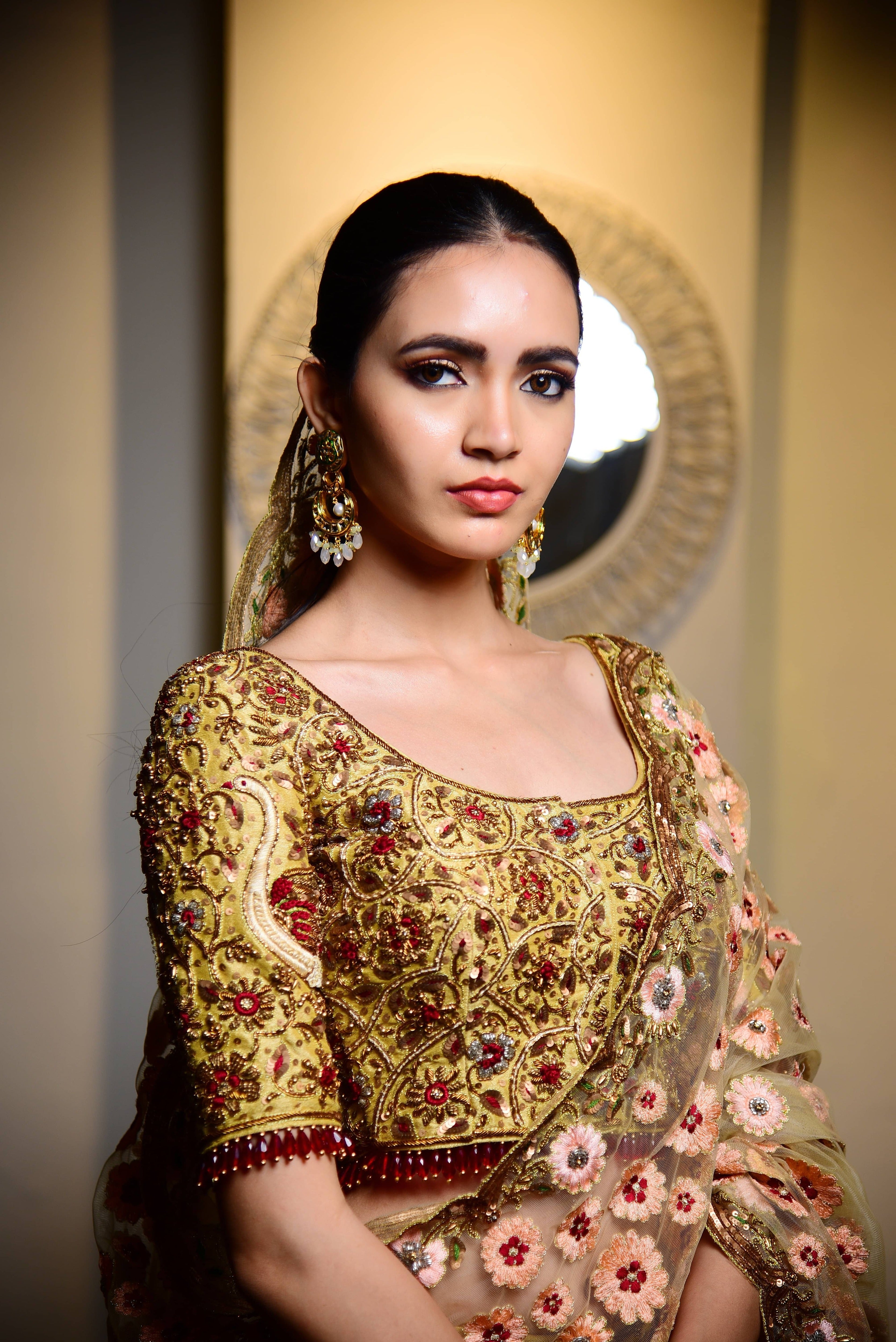 The model's top half is captured showing the intricate work on the front side of the blouse. This raw silk lehenga with heavy intricate resham, sequins, beads,stonework embellishments all over the lehenga, blouse and tulle dupatta.