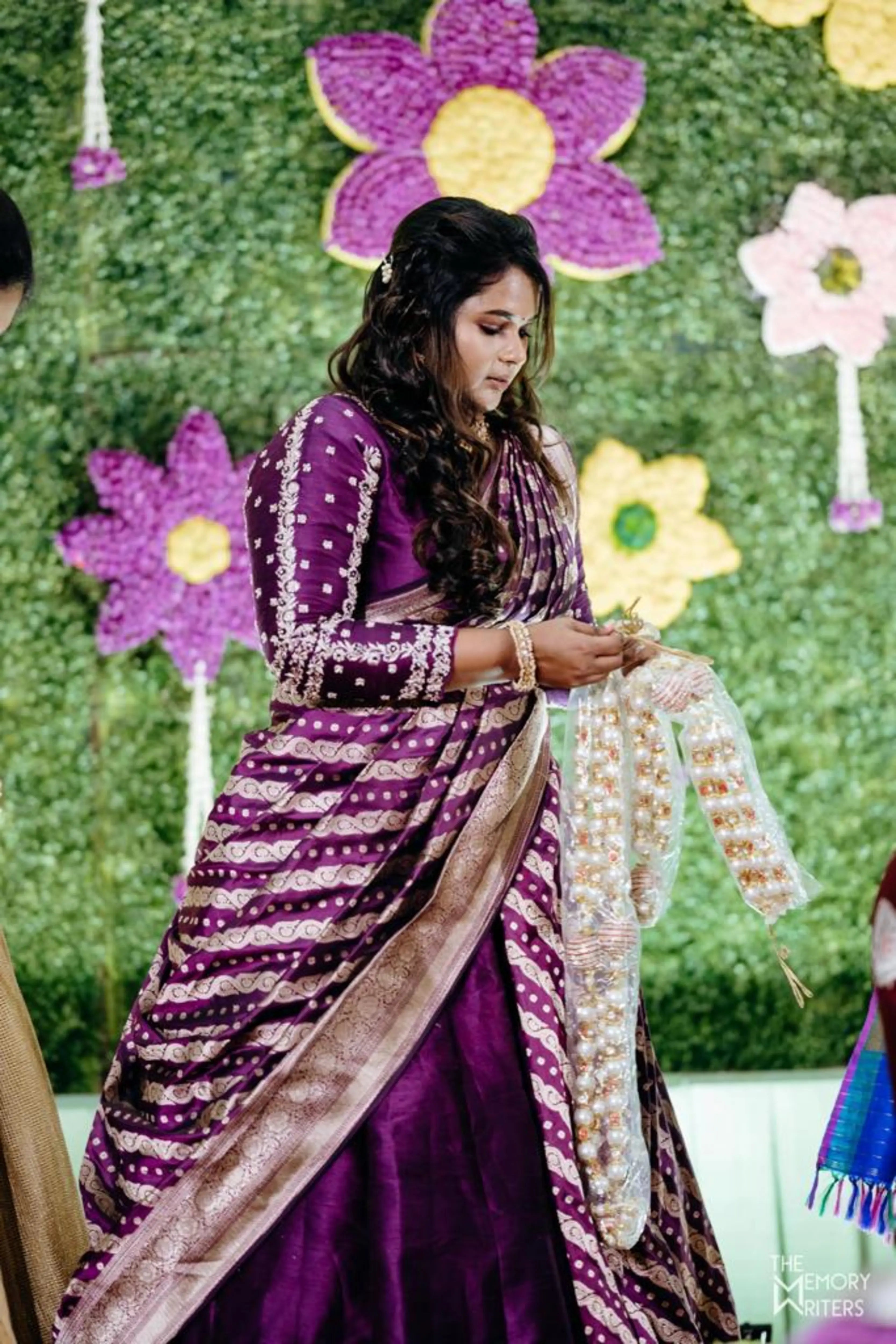 Santhoshi Babu posing for her son's 1st birthday in a violet silk half saree handcrafted by team Archana Karthick.