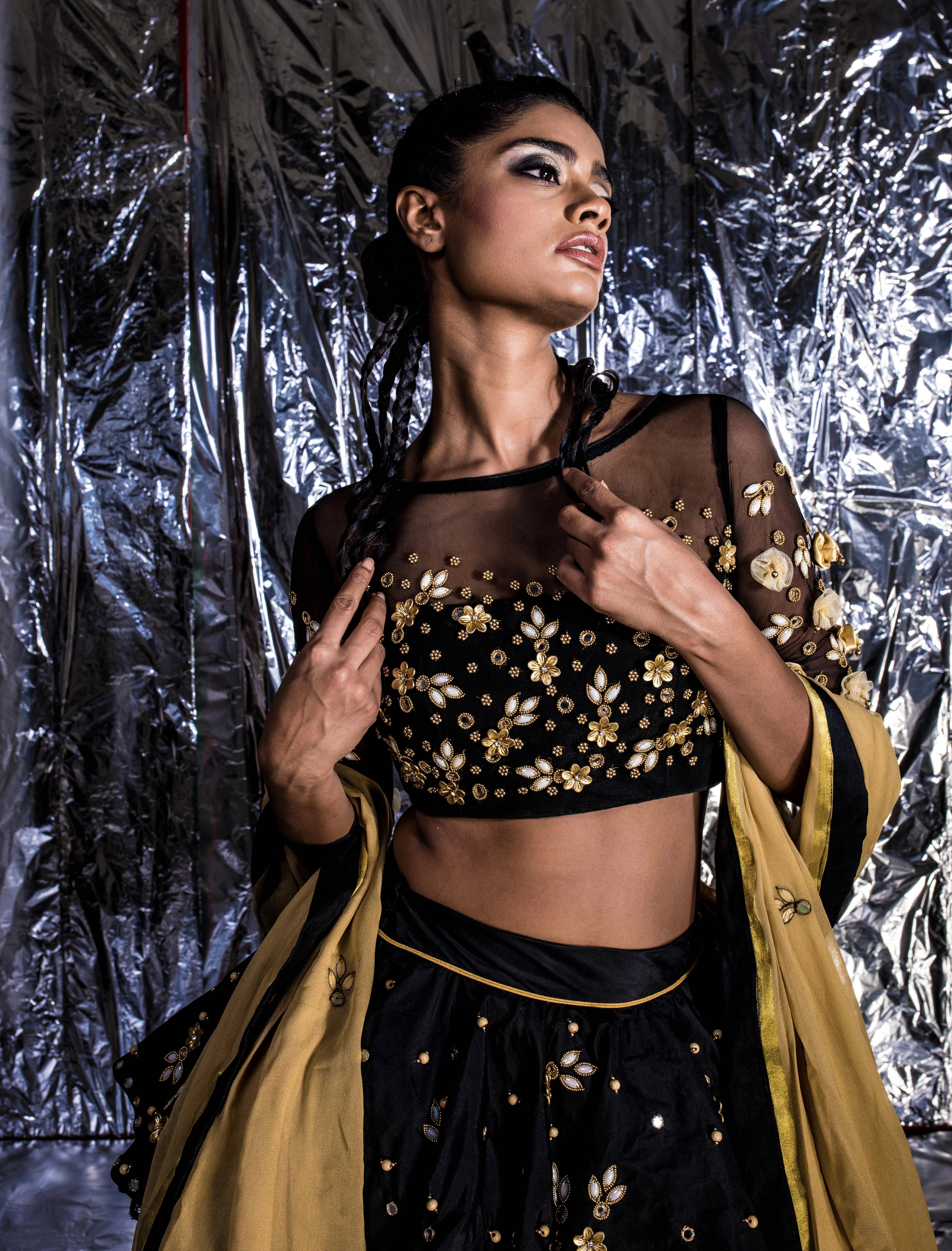 Supermodel Archana Akil Kumar looking sideways in a black taffeta lehenga with a gold georgette dupatta intricately handcrafted with appliques, pearls, mirror and beads.