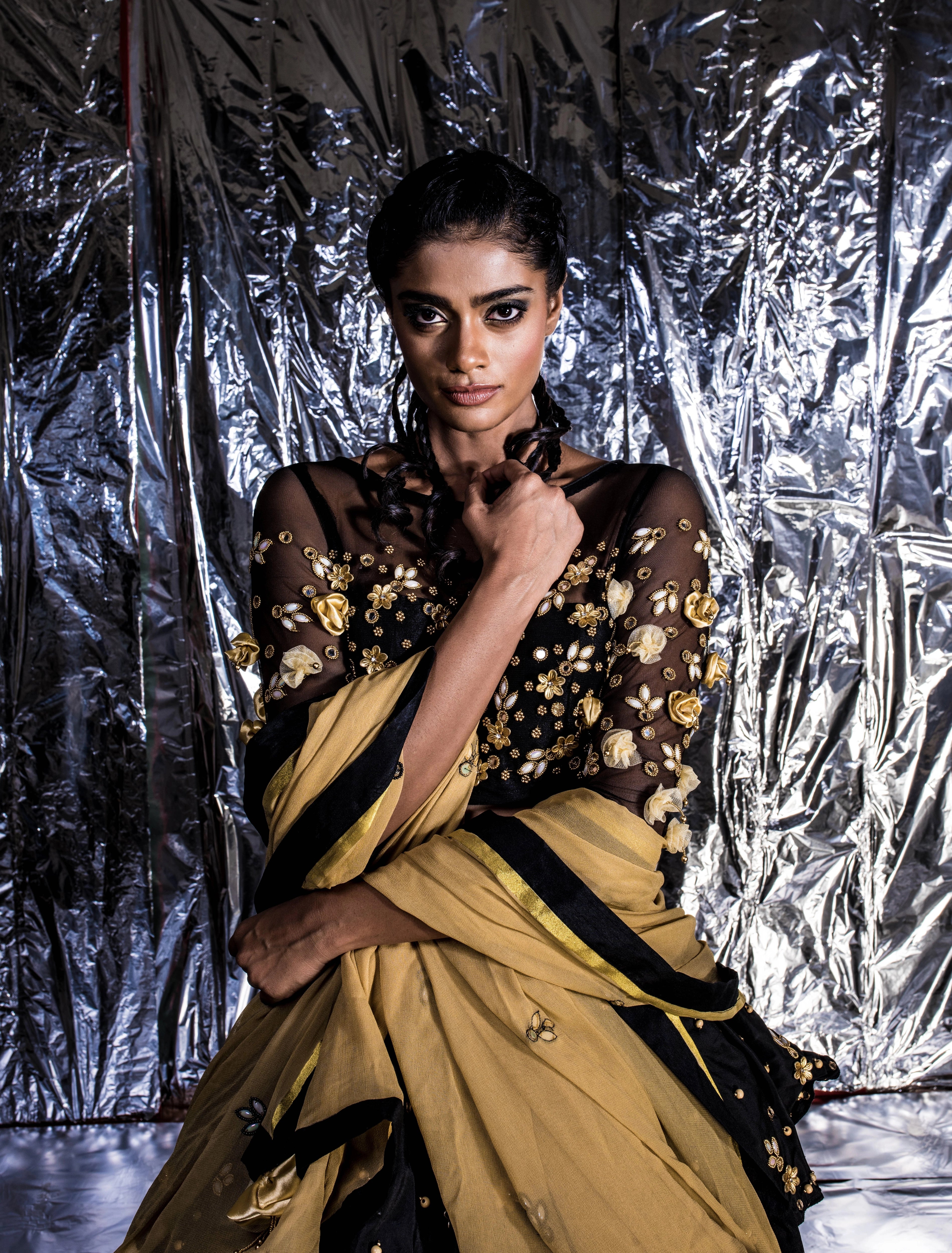 Supermodel Archana Akil Kumar looking straight at camera in a black taffeta lehenga with a gold georgette dupatta intricately handcrafted with appliques, pearls, mirror and beads.