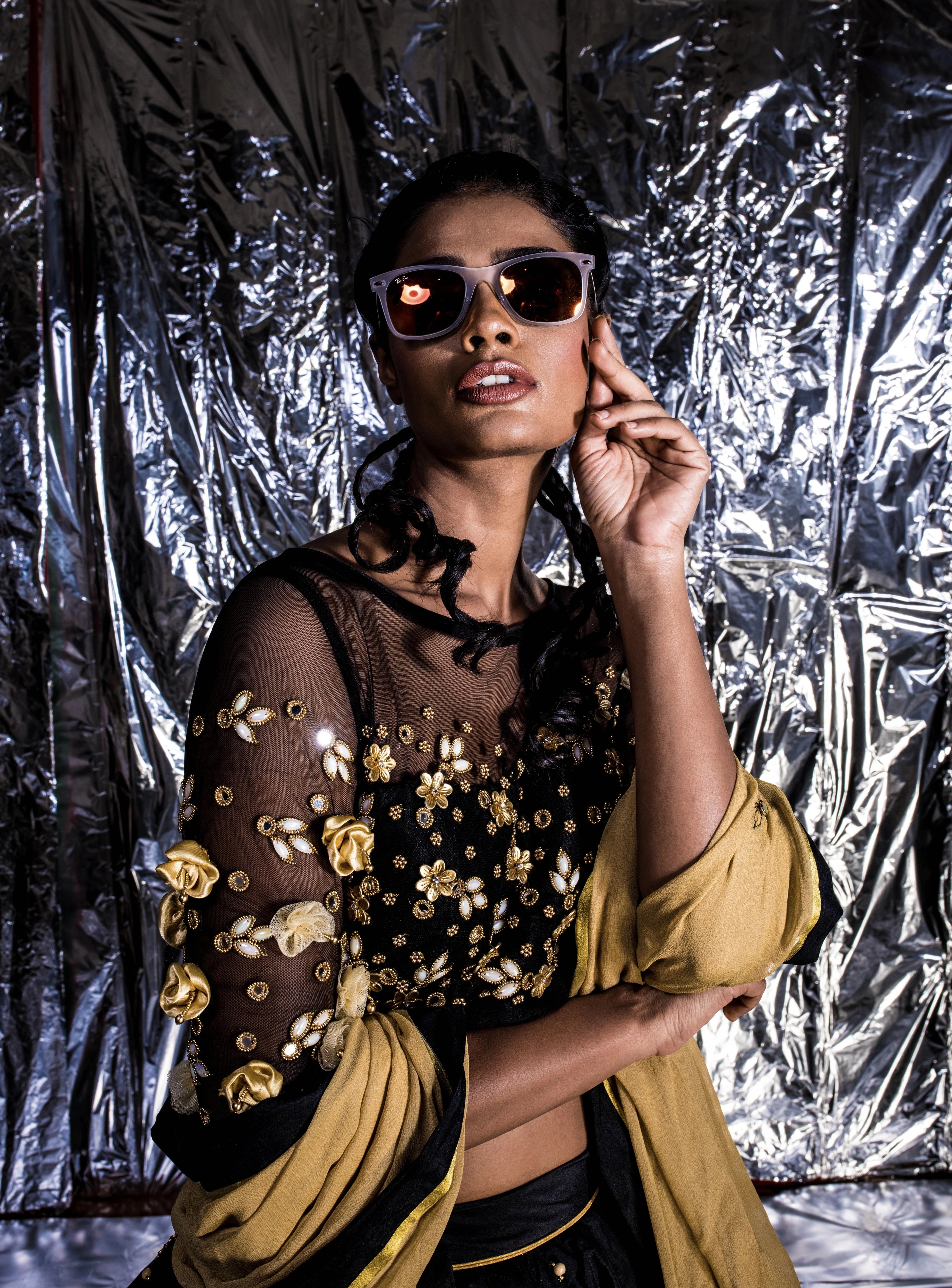 Supermodel Archana Akil Kumar posing for a closeup in sunglasses in a black taffeta lehenga with a gold georgette dupatta intricately handcrafted with appliques, pearls, mirror and beads.