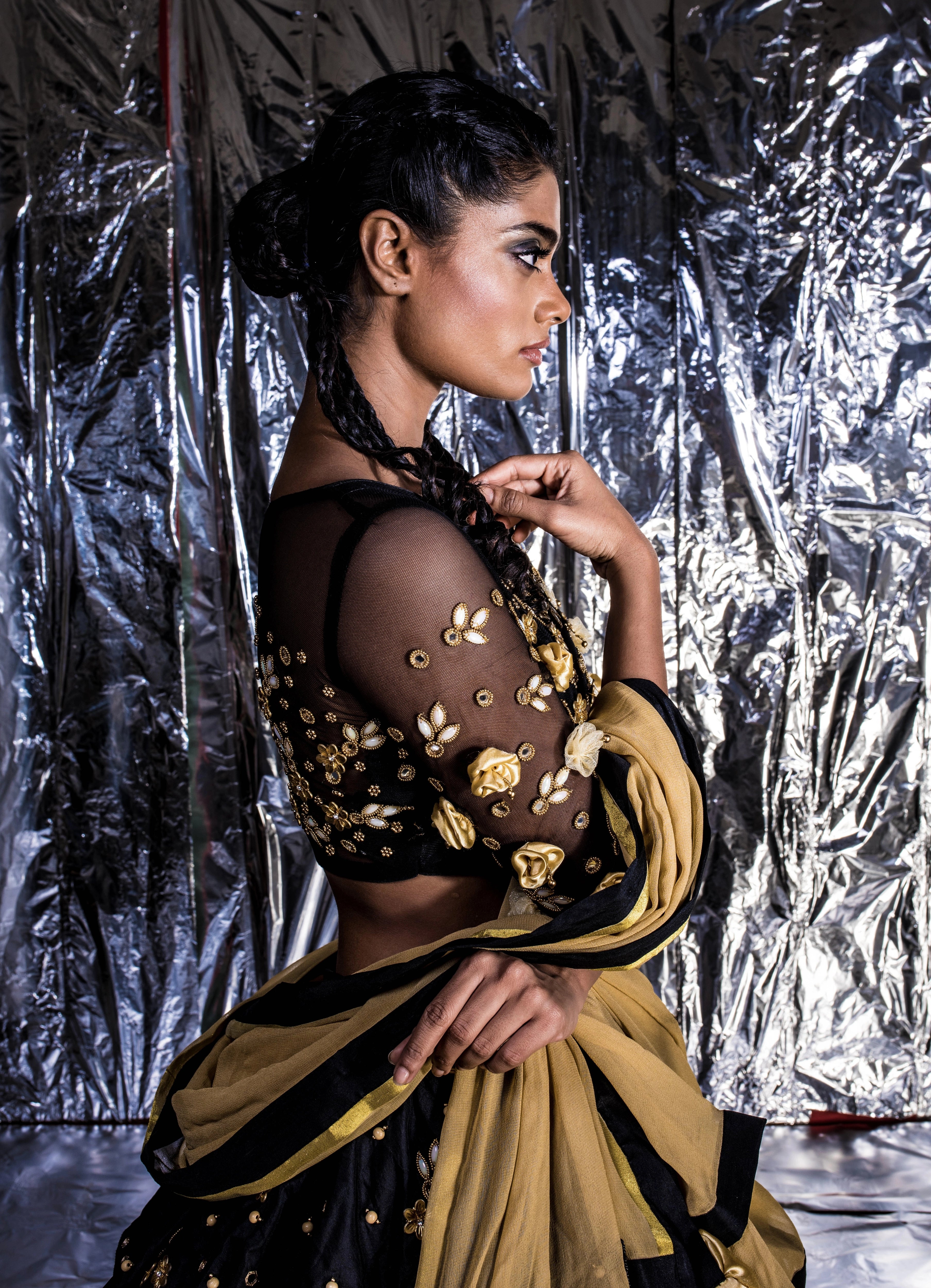 Supermodel Archana Akil Kumar posing for sleeve details in a black taffeta lehenga with a gold georgette dupatta intricately handcrafted with appliques, pearls, mirror and beads.