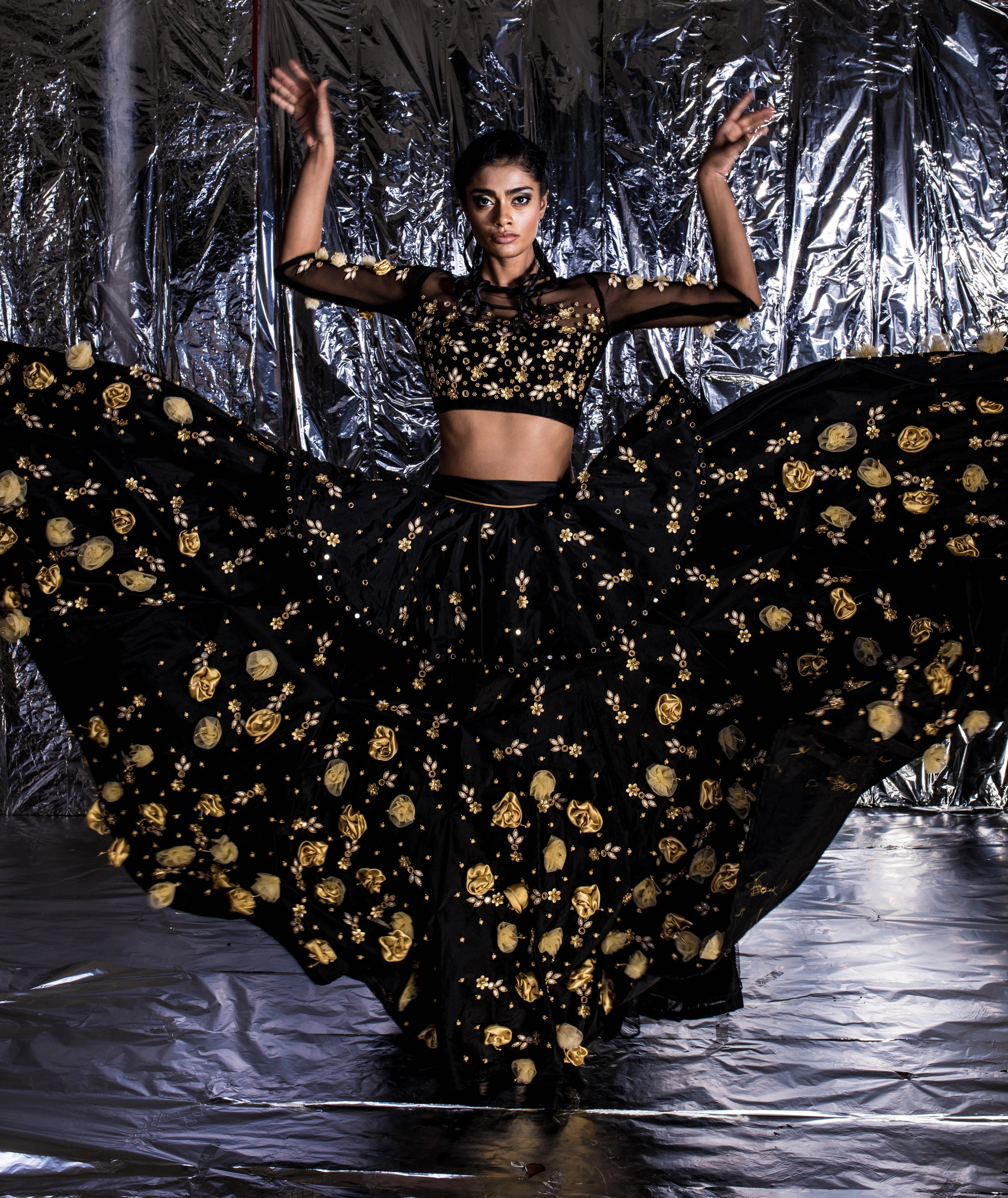 Supermodel Archana Akil Kumar posing like a pro in a black taffeta lehenga with a gold georgette dupatta intricately handcrafted with appliques, pearls, mirror and beads.