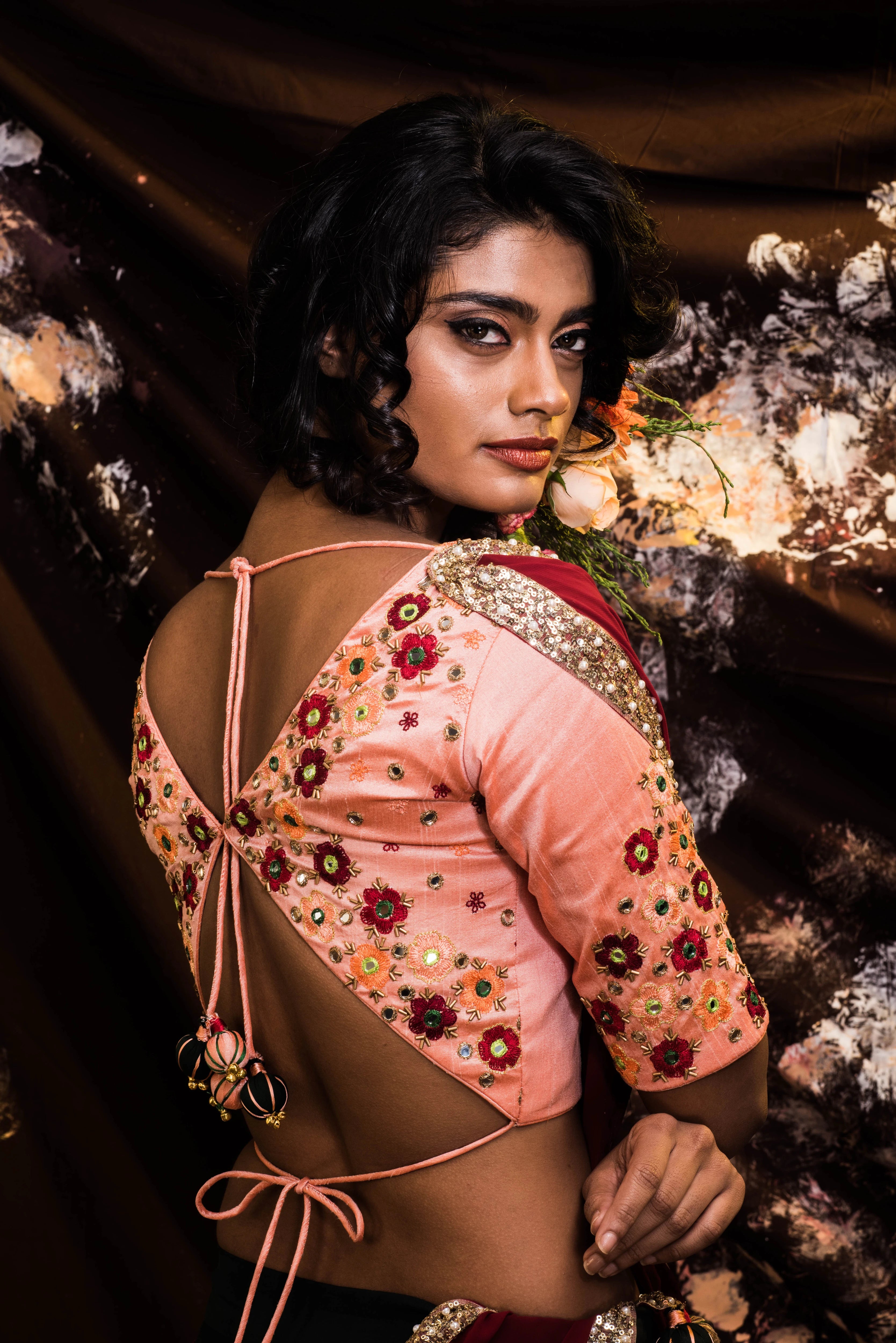 Supermodel Archana Akil Kumar showcasing back blouse detailings in a rawsilk peach and bottle green lehenga with a maroon georgette dupatta intricately handcrafted by team Archana Karthick.