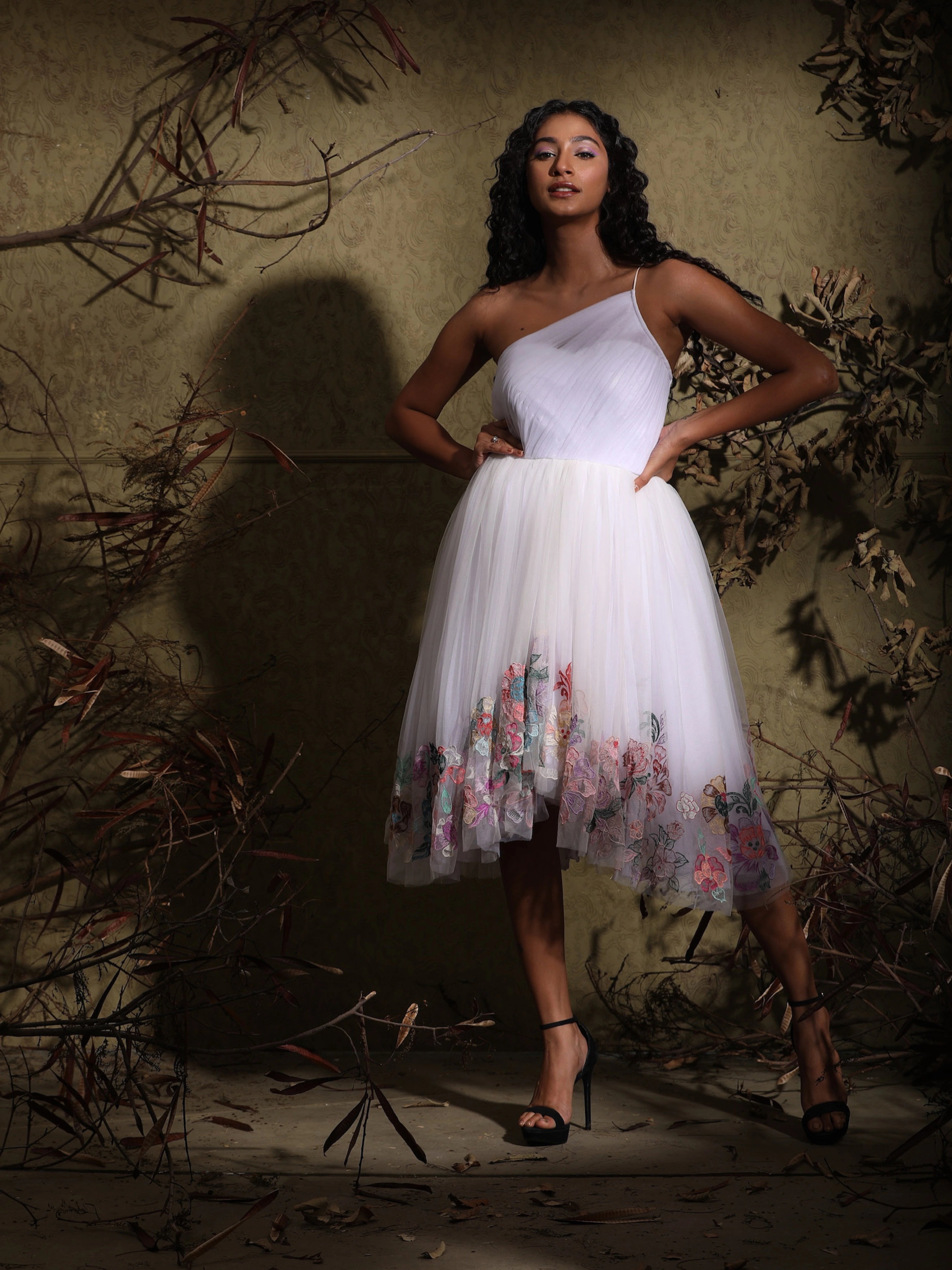Anukreethy Vas, Miss India 2018, confidently posing in a white one-shoulder tulle dress, showing the intricate pastel floral embroidery along the asymmetric hem, a luxurious Archana Karthick design.
