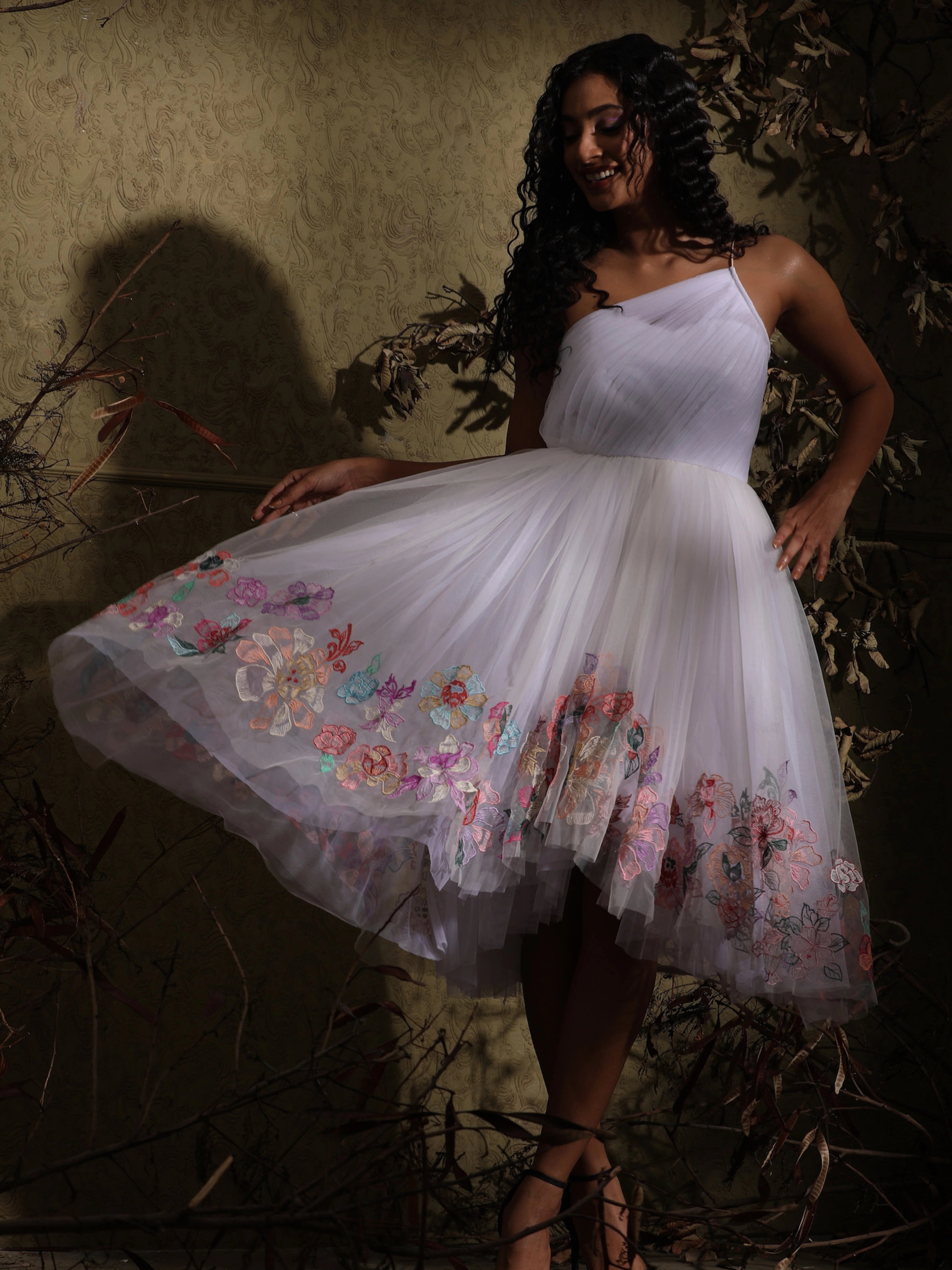 Anukreethy Vas, Miss India 2018, showcasing the back detail and flow of a white tulle one-shoulder dress with pastel floral embroidery, a stunning designer party dress by Archana Karthick.