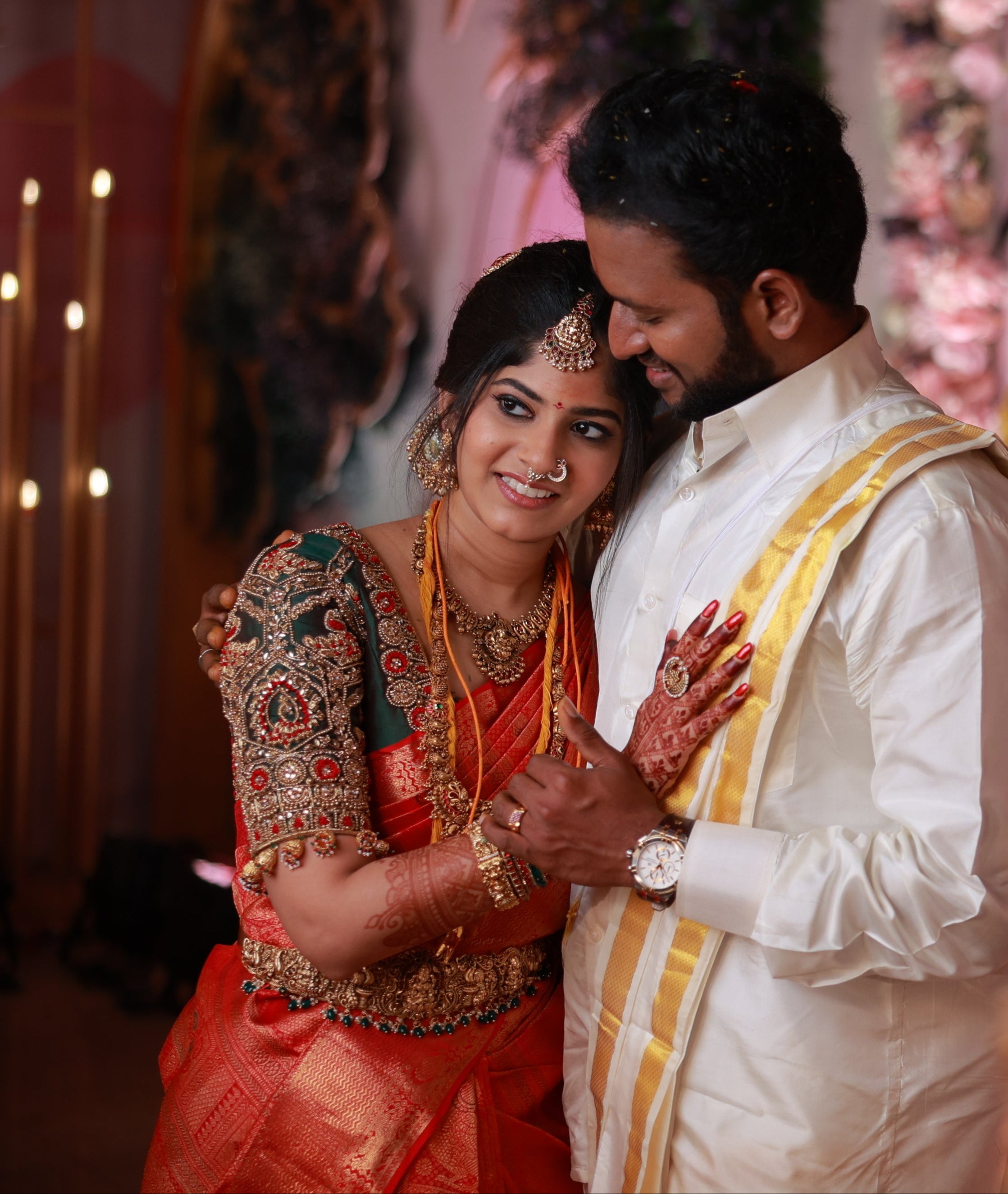 Kaviya, a bride is in a green silk blouse designed by Archana Karthick. She is posing for the picture with her head resting on the groom's chest. They are both smiling. The blouse has been handcrafted with intricate detailings involving beads, resham,zardozi and the blouse sleeves also have "jhumkas" at the seam. The bride's mehendi is seen on her right hand.