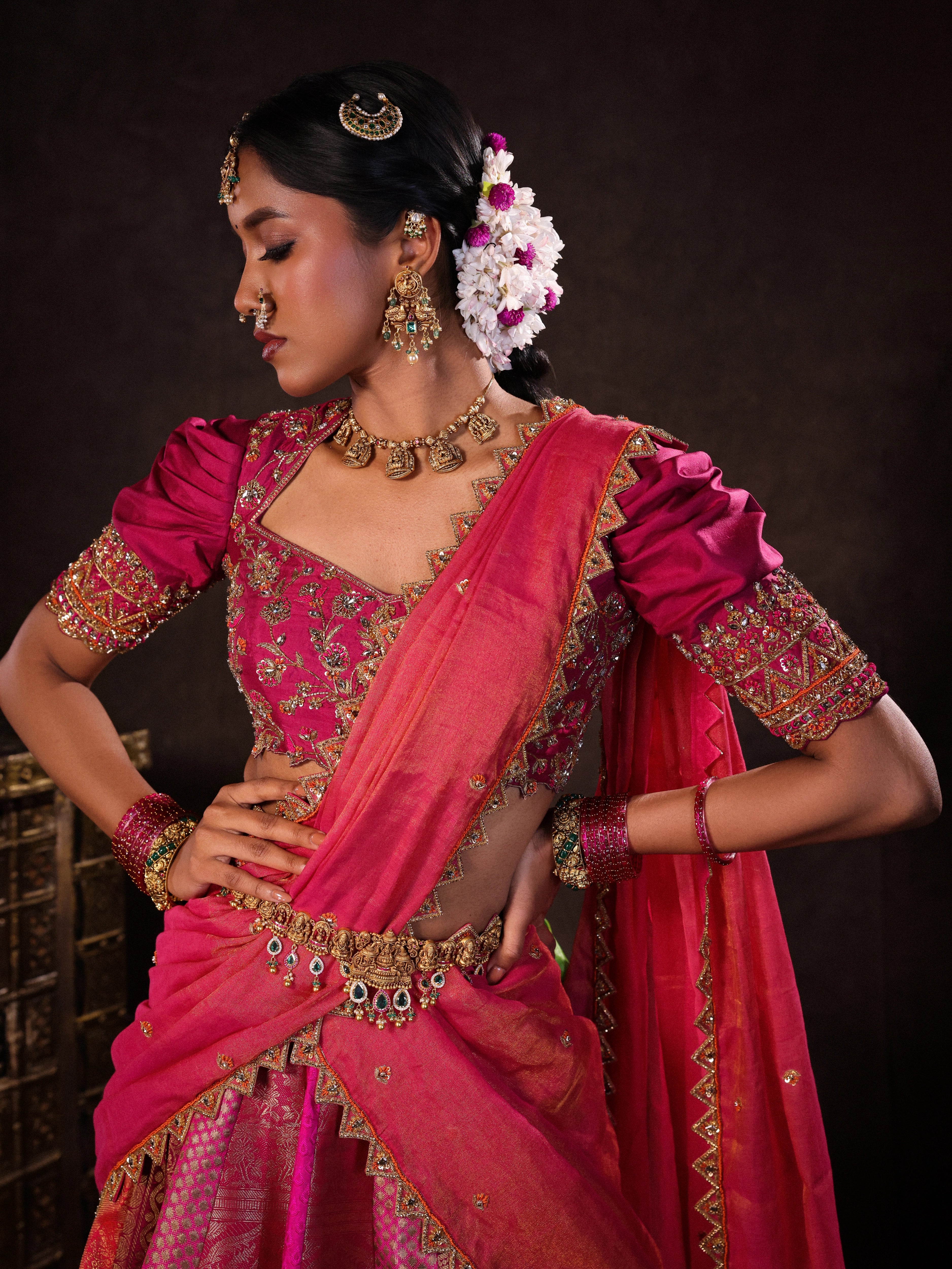 Model Gayathri Dhanasekar in a pink & orange kanjeevaram silk half saree with glass bangles and NAC jewellery.