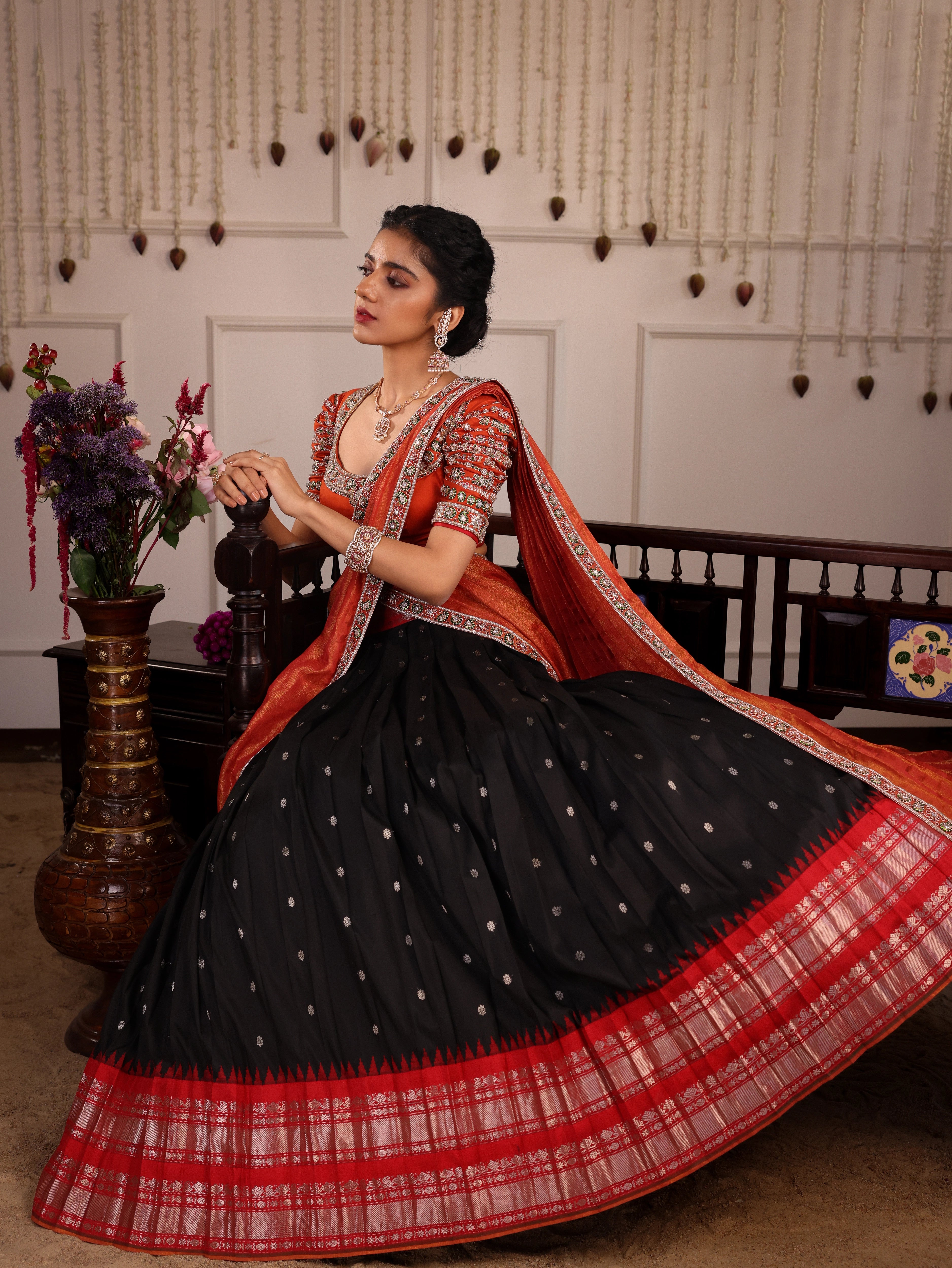 Model Himanshi seated in black & orange kanjeevaram silk half saree with vummidi bangaru jewllery
