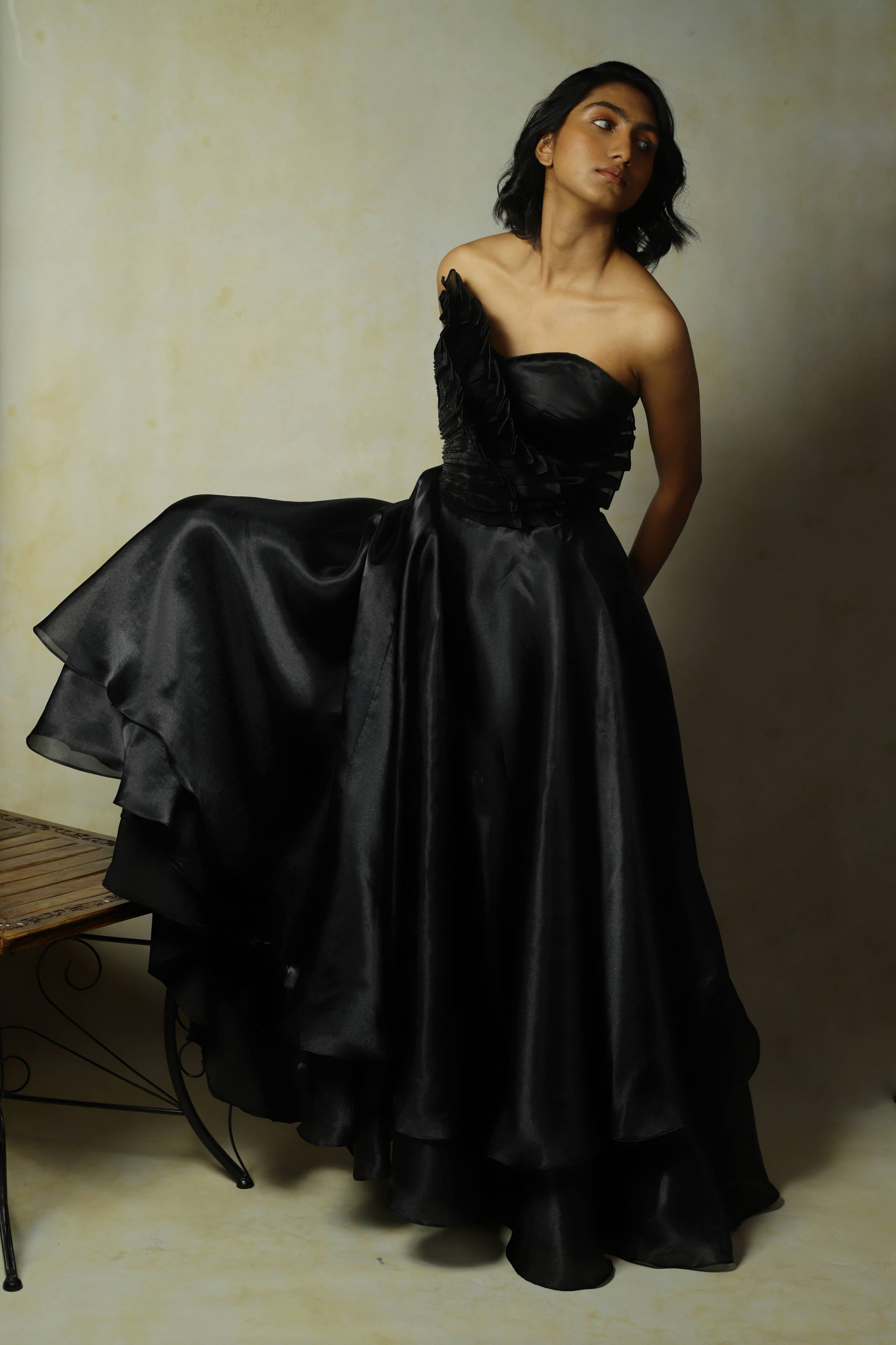 model posing in black tissue organza with structured upper body, standing and looking to her left. 