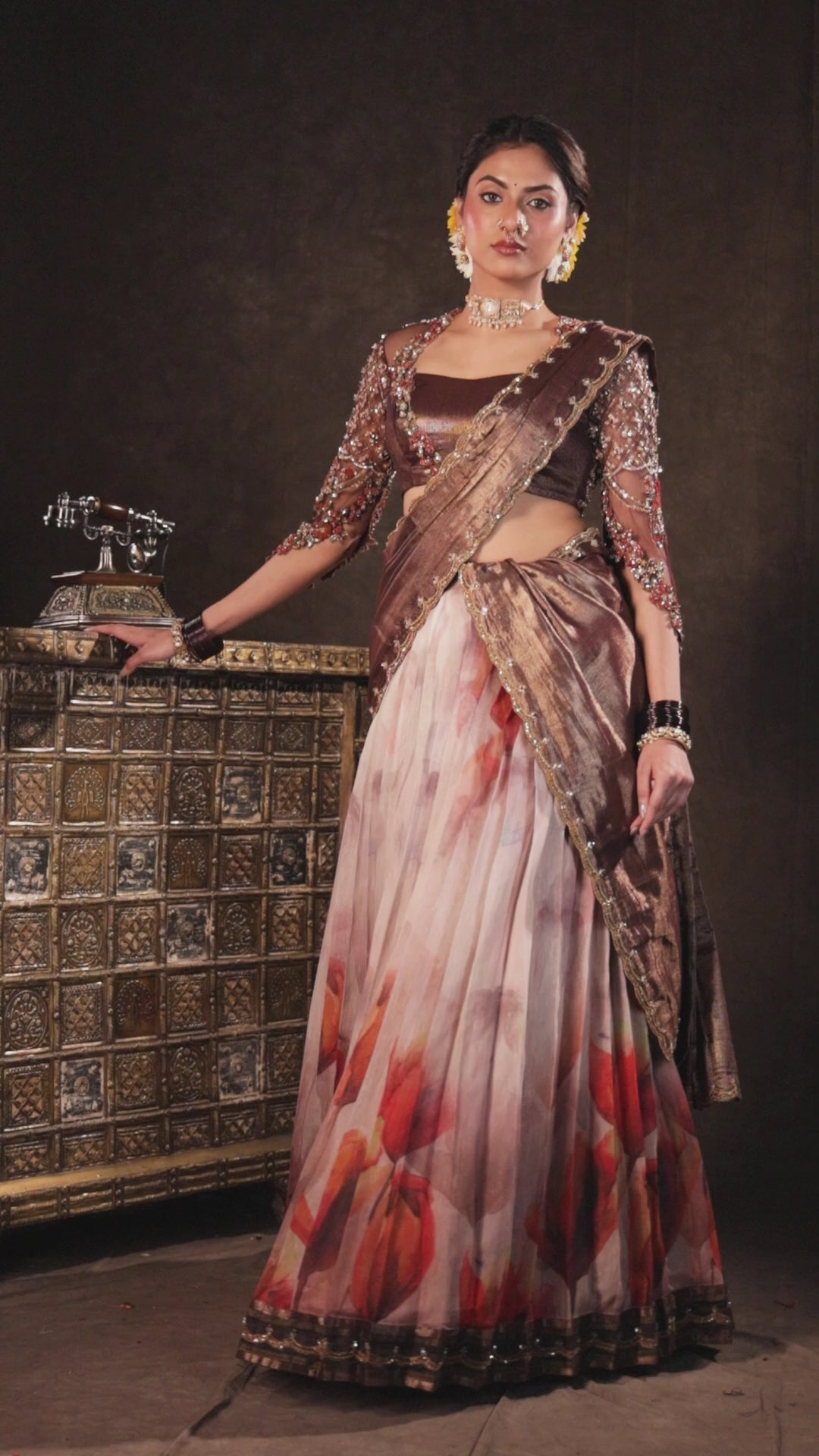 Model Dr Sree Advaita for a campaign video in a brown & printed ivory silk half saree set handcrafted with zardozi, resham, cutdana, sequins & rhinestones. Team Archana Karthick completed the style with brown glass bangles, a ring, jhumkas, nose ring and a maang tikka.