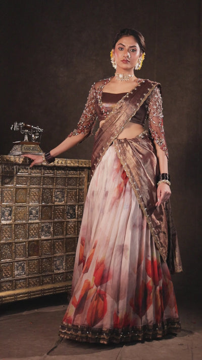 Model Dr Sree Advaita for a campaign video in a brown & printed ivory silk half saree set handcrafted with zardozi, resham, cutdana, sequins & rhinestones. Team Archana Karthick completed the style with brown glass bangles, a ring, jhumkas, nose ring and a maang tikka.